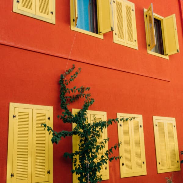 Part of red facade of building with yellow wooden shutters 