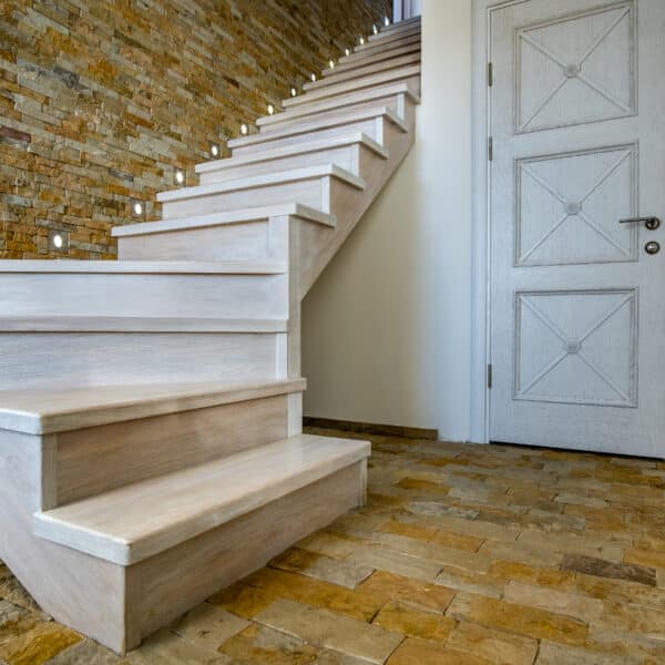 Stylish wooden contemporary staircase inside loft house interior  Modern hallway with decorative limestone brick walls and white oak stairs 