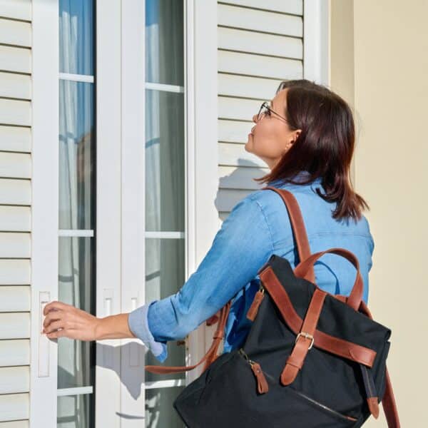 Woman with backpack opening shutters outside doors on window